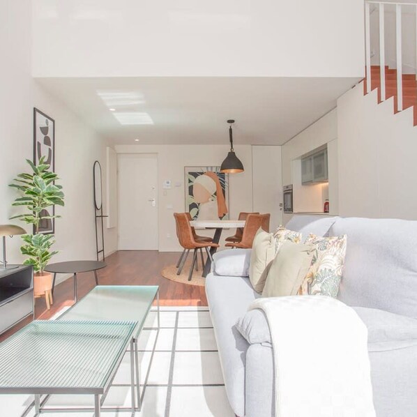 Un salon moderne avec un canapé, une table à manger et un escalier.