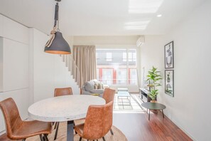 A modern dining area with a round table, leather chairs, and a pendant light. - Liiiving in Porto - Luxury Gallery Apartment I (Porto)