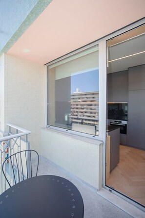 A modern kitchen with a large window, a dining area with a table and chairs, and a view of a building across the street. - Allegro Boutique Apartment B by Liiiving (Porto)