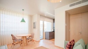 A modern living room with a round wooden table, two zebra-striped chairs, a green pendant light, a green sofa with a plaid pillow, and a wooden door. - Allegro Boutique Apartment B by Liiiving (Porto)