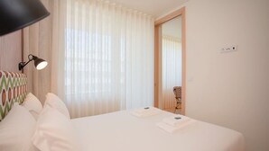 A hotel room with a bed, white curtains, a lamp, and a mirror. - Allegro Boutique Apartment B by Liiiving (Porto)