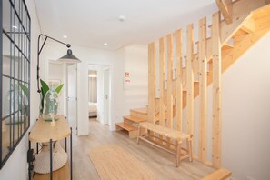 A modern interior with a wooden staircase, a bench, and a table with a glass container. - Liiiving in Porto - Downtown Quiet House (Porto)