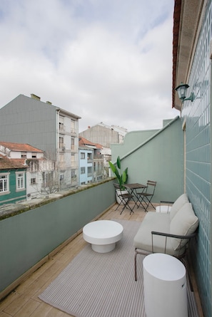 Un balcón con zona de estar, planta en maceta y vista panorámica de la ciudad.