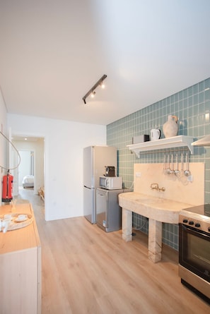 Una cocina moderna con encimera de mármol, electrodomésticos de acero inoxidable y salpicadero de azulejos azules.