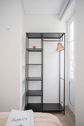 A room with a black metal wardrobe, a white door, and a window with blinds.