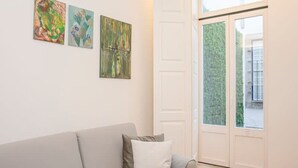 En moderne stue med en grå sofa, en hvid dør og tre abstrakte billeder på væggen.