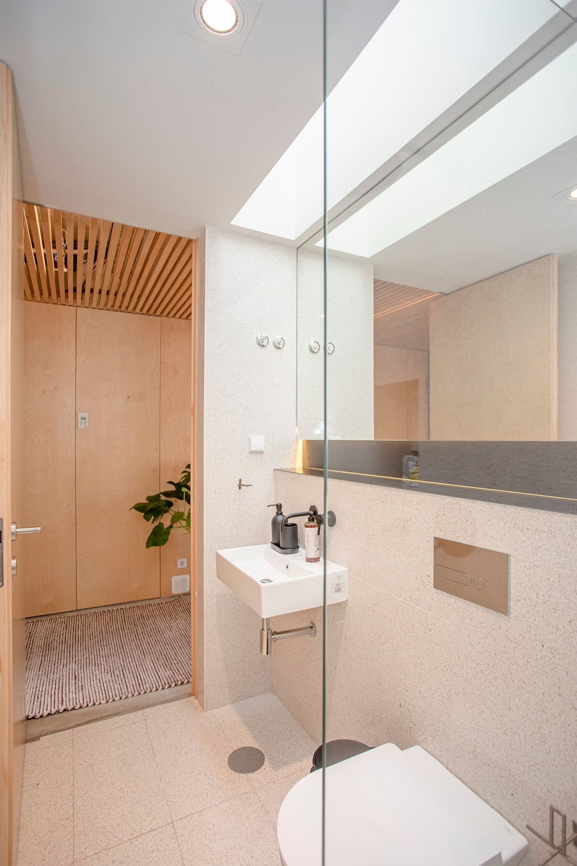A modern bathroom with a wooden shower enclosure, a white sink, and a large mirror.
