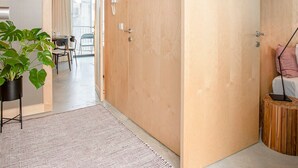 A modern interior with a wooden door, a dining area with chairs, a plant, and a small round table. - Liiiving in Porto - Bolh o Trendy Apartment III (Porto)