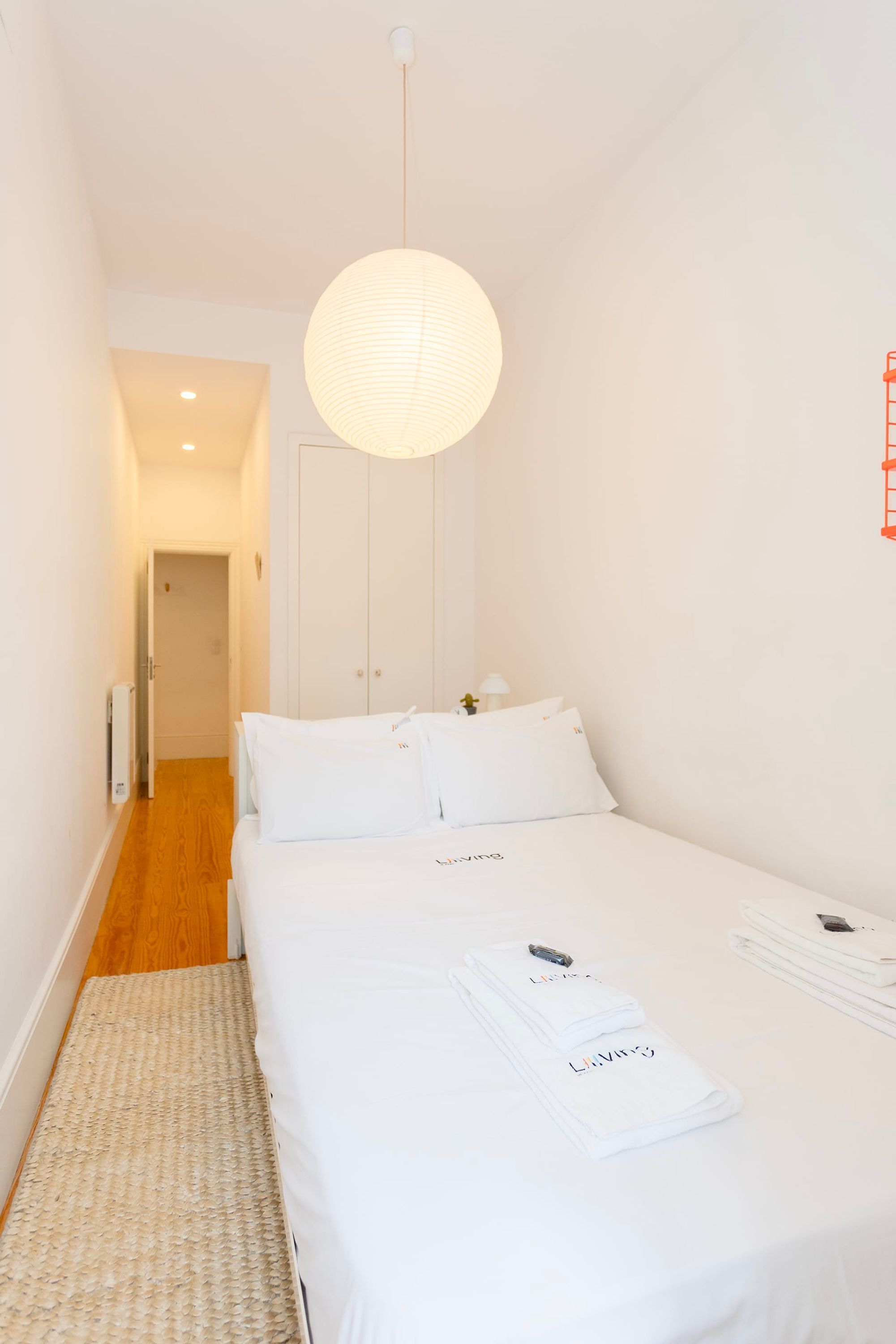 Habitació d'hotel amb un llit, un llum penjant, una porta i un radiador.