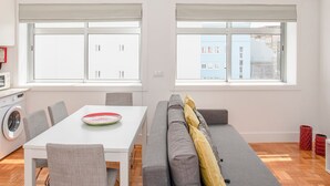 Een modern appartement met een eethoek, een bank en een wasmachine.