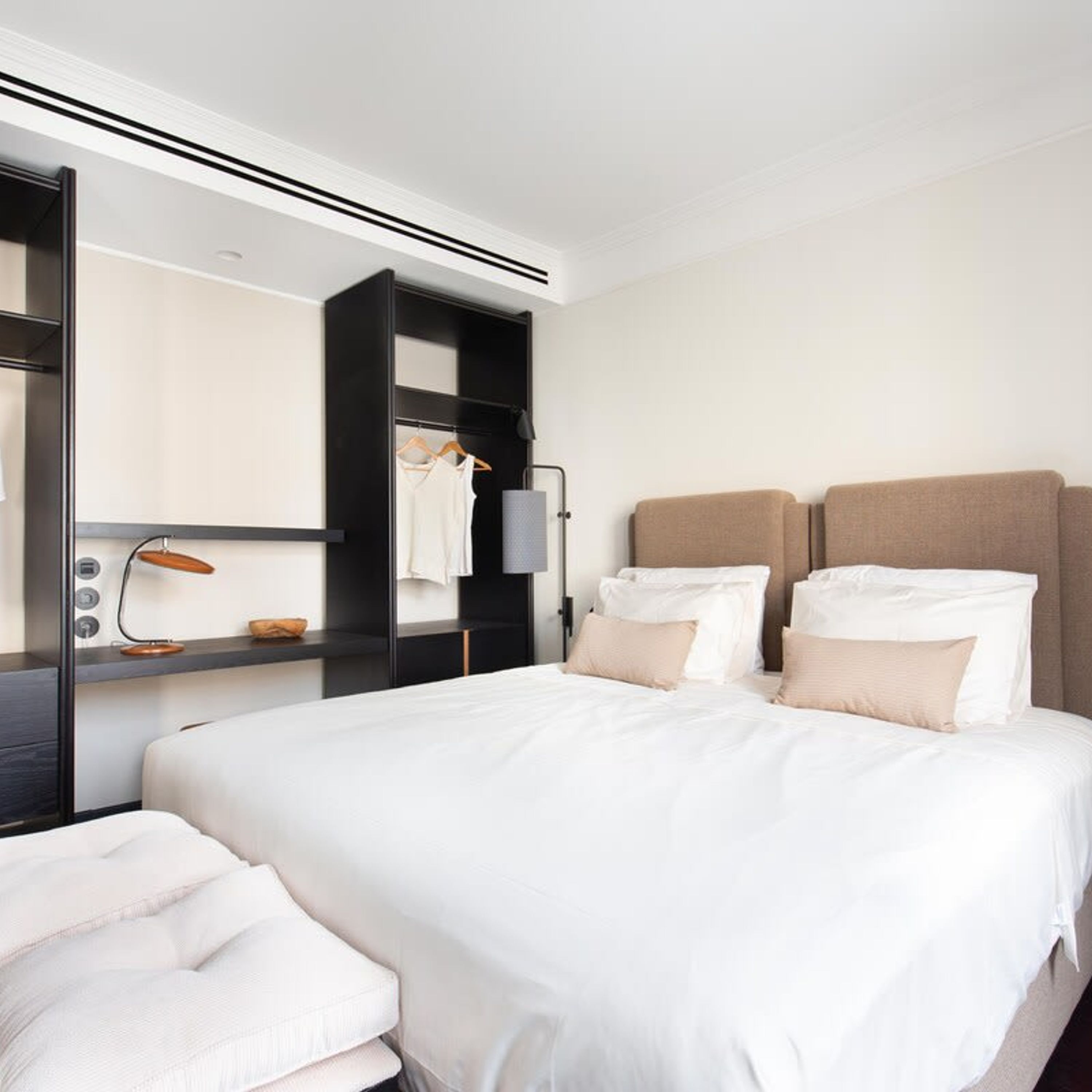Quarto de hotel moderno com uma cama grande, uma mesa de cabeceira, um guarda-roupa e um espelho.