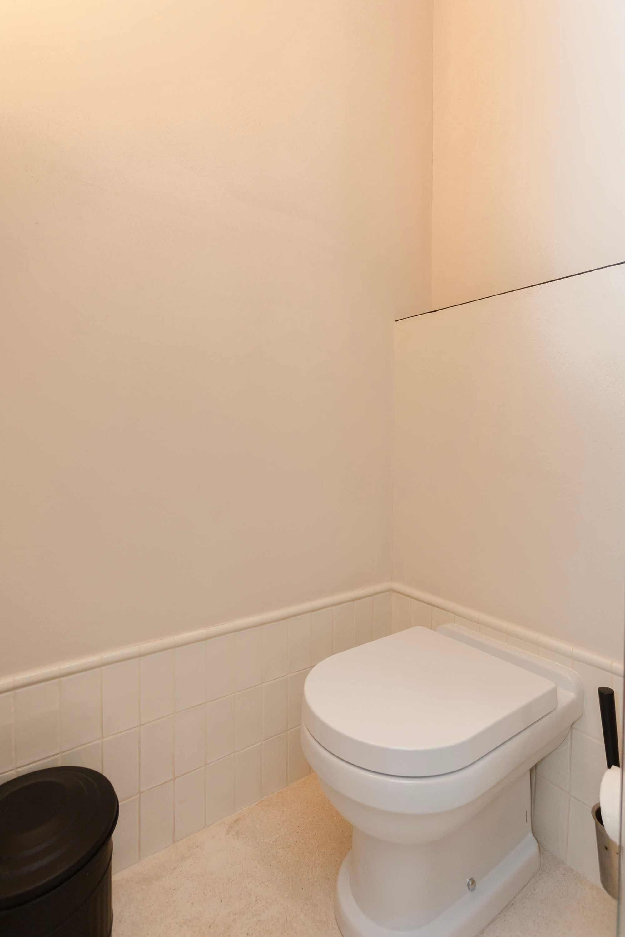 Een wit toilet in een badkamer met witte tegels op de muren en vloer.