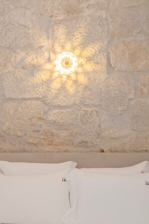 Una stanza con una parete in pietra e un lampadario circolare.