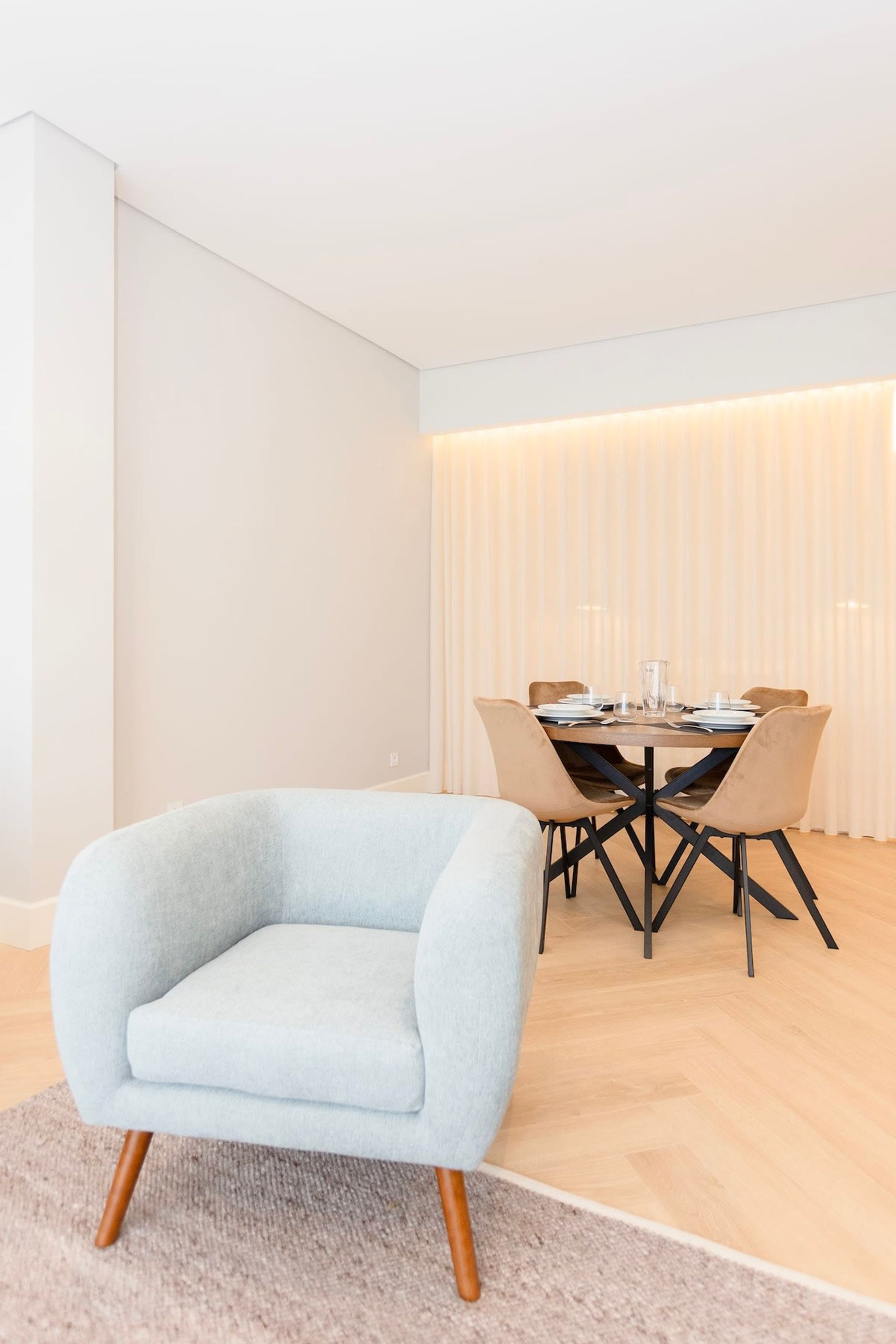 Un espace repas moderne avec une table ronde, un fauteuil bleu clair et un plancher en bois.