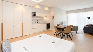 A modern, well-lit apartment with a dining area, kitchen, and a large bed. - Liiiving in Porto - Luxury Design Apartment I (Porto)
