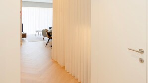 A hallway with a wooden floor leading to a room with a white door and a curtain. - Liiiving in Porto - Luxury Design Apartment I (Porto)