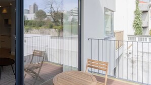 A modern balcony with a glass door, a round wooden table, and two chairs. - Liiiving in Porto - Luxury Design Apartment I (Porto)