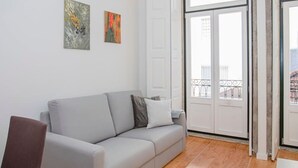 Un salon moderne avec un canapé gris, deux tableaux abstraits et un plancher en bois.