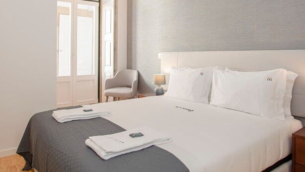 Une chambre d’hôtel avec un grand lit, une chaise, une table de chevet et une fenêtre.