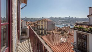 Un balcon offrant une vue sur le paysage urbain, avec des bâtiments et une étendue d’eau.