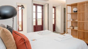 Une chambre à coucher avec un lit, une armoire en bois, un bureau et une lampe suspendue.
