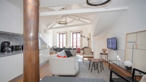 Un loft spacieux comprenant une cuisine, un coin repas et un salon. Une grande colonne en cuivre constitue un élément remarquable.