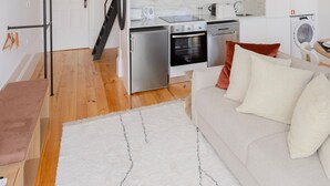 A compact kitchen with white cabinets, a stainless steel refrigerator, and a built-in oven. - Liiiving in Porto - Mezzanine Delight Apartment (Porto)