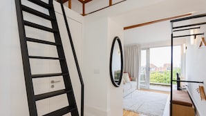 A modern interior with a black metal staircase, a large mirror, and a view to a balcony with a sofa. - Liiiving in Porto - Mezzanine Delight Apartment (Porto)