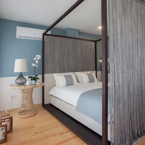 A bedroom with a four-poster bed, a bedside table with a lamp, and a potted plant. - Liiiving in Porto Downtown Luxury Studio (Porto)