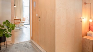 Un intérieur moderne avec une porte en bois, un coin repas comprenant des chaises et une table, et une plante.