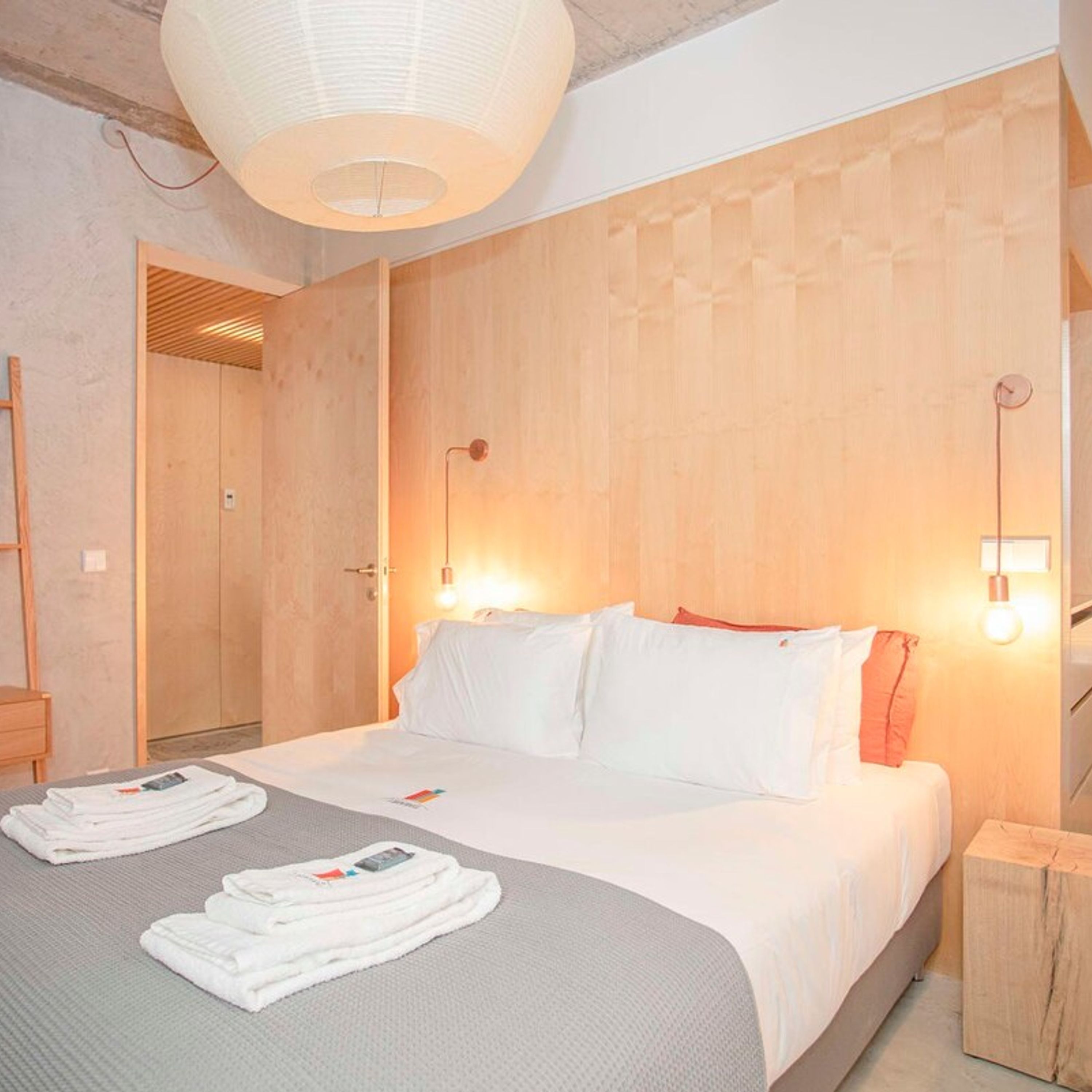 Una camera d'albergo con un letto grande, due comodini e una testiera in legno.