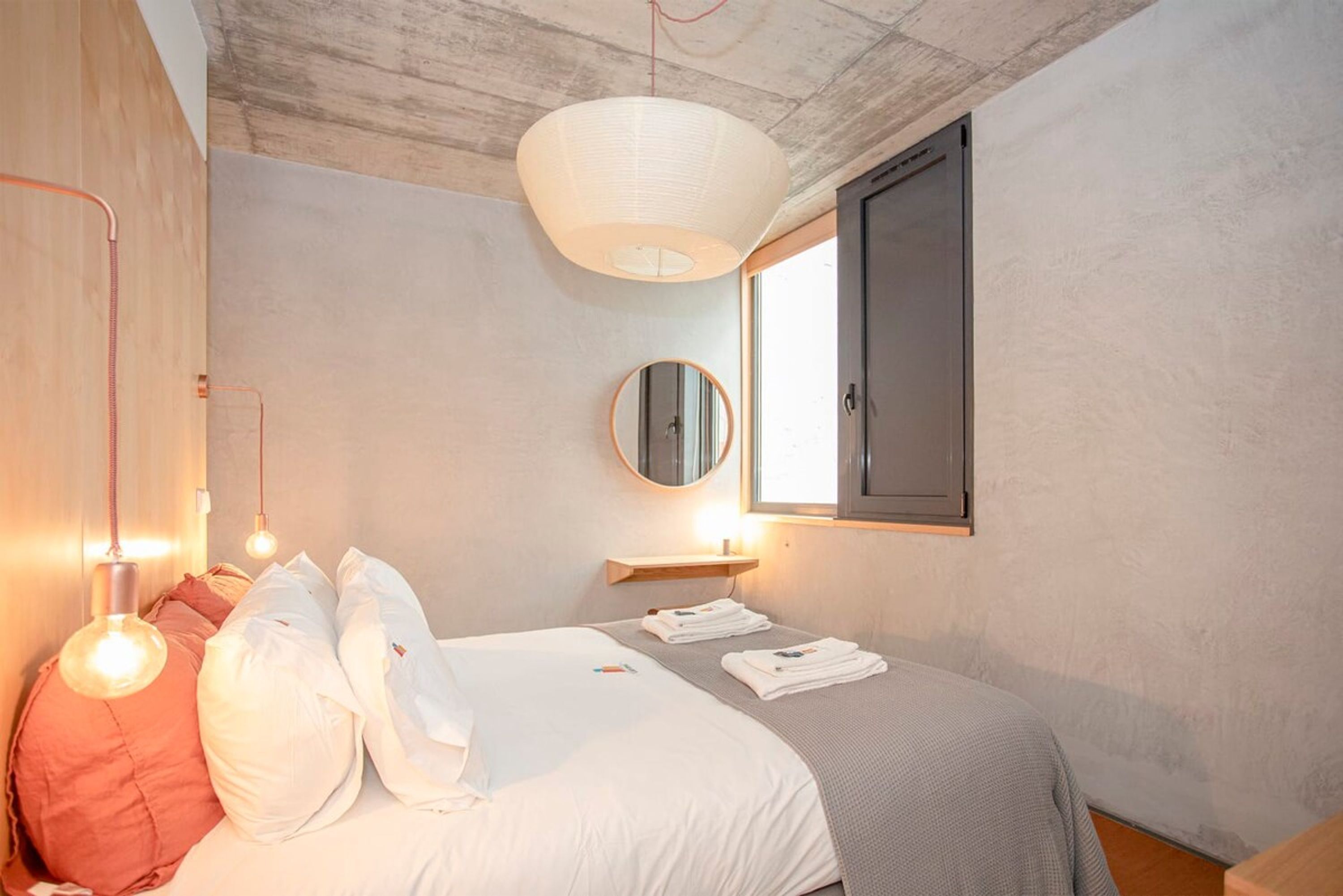 Una camera da letto con un letto, lampade sui comodini, uno specchio e una finestra.