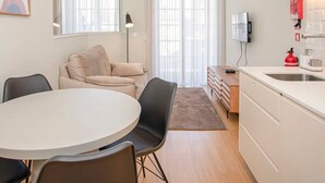 Une cuisine moderne avec des meubles blancs, un four à micro-ondes et un extincteur rouge.