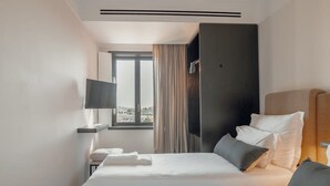 A hotel room with two beds, a TV, a window with curtains, and a view of the outdoors. - Liiiving in Porto - Casa Duque Apartment IV (Porto)