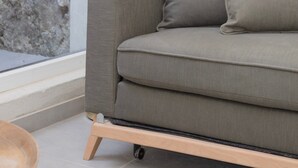 Ein modernes Wohnzimmer mit einem grauen Sofa, einer Stehlampe und einer Steinwand.