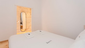 Ein schlicht eingerichtetes Hotelzimmer mit einem Bett, einem Spiegel und einem kleinen Tisch mit einem Handtuch.