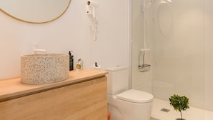 Ein modernes Badezimmer mit rundem Spiegel, freistehendem Waschbecken, Toilette und Duschkabine.