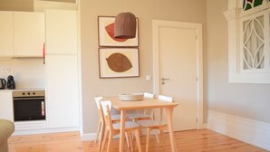 Une cuisine avec des meubles blancs, une table à manger en bois avec des chaises et un luminaire suspendu.