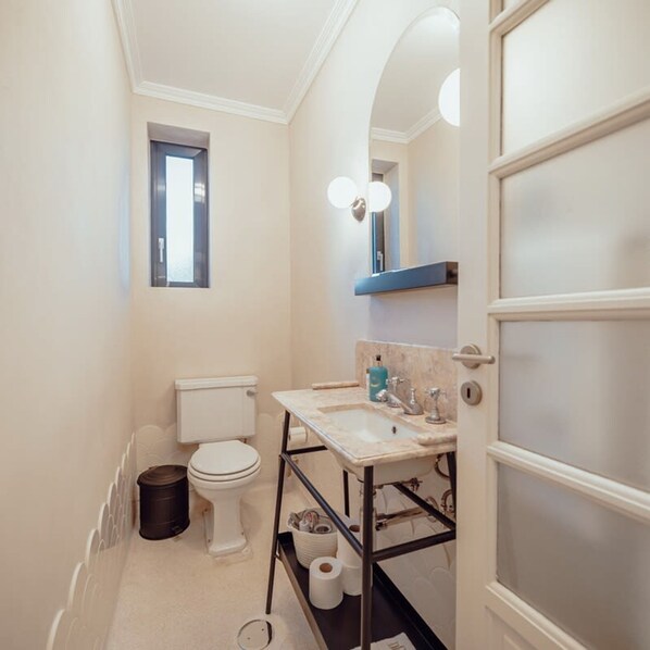 Une petite salle de bain comprenant des toilettes, un lavabo et une petite fenêtre.