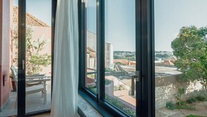 A room with a large window, a view of a courtyard, and a door leading outside. - Liiiving in Porto - Casa Duque Apartment III (Porto)