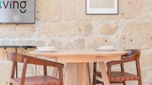 A dining area with a stone wall, a framed picture, and a table with chairs. - Liiiving In Gaia - The Wine Side V (Vila Nova de Gaia)