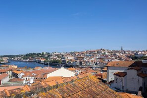 A coastal cityscape with historic buildings, a river, and a prominent statue.
