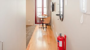 A hallway with a dining area, a fire extinguisher, a phone, and a window with curtains. - Liiiving in Porto Historic Cl Rigos Studio - 3F (Porto)