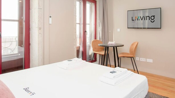 A hotel room with a bed, a small table, two chairs, a ceiling light, and a sign on the wall. - Liiiving in Porto Historic Cl Rigos Studio - 3F (Porto)