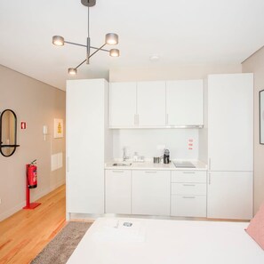 A modern, compact kitchen with white cabinetry, a built-in oven, and a coffee maker. - Liiiving in Porto Historic Cl Rigos Studio - 3F (Porto)