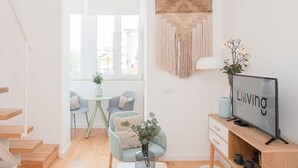 Ein modernes Wohnzimmer mit Fernseher, Sitzecke und Treppe.