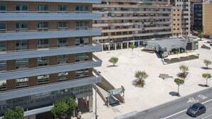 Un hotel de varios pisos con diseño moderno, que cuenta con un patio central con árboles y un estacionamiento.