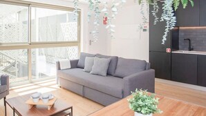 A modern living room with a grey sofa, wooden coffee table, and hanging plants. - NAX Apartment D by Liiiving (Porto)