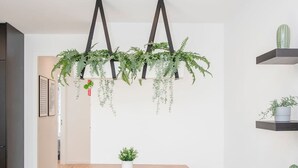 A modern kitchen with a wooden table, two stools, hanging plants, and a cactus on a shelf. - NAX Apartment D by Liiiving (Porto)