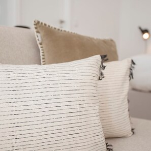 Una cama con dos almohadas, una a rayas y otra de color beige liso.